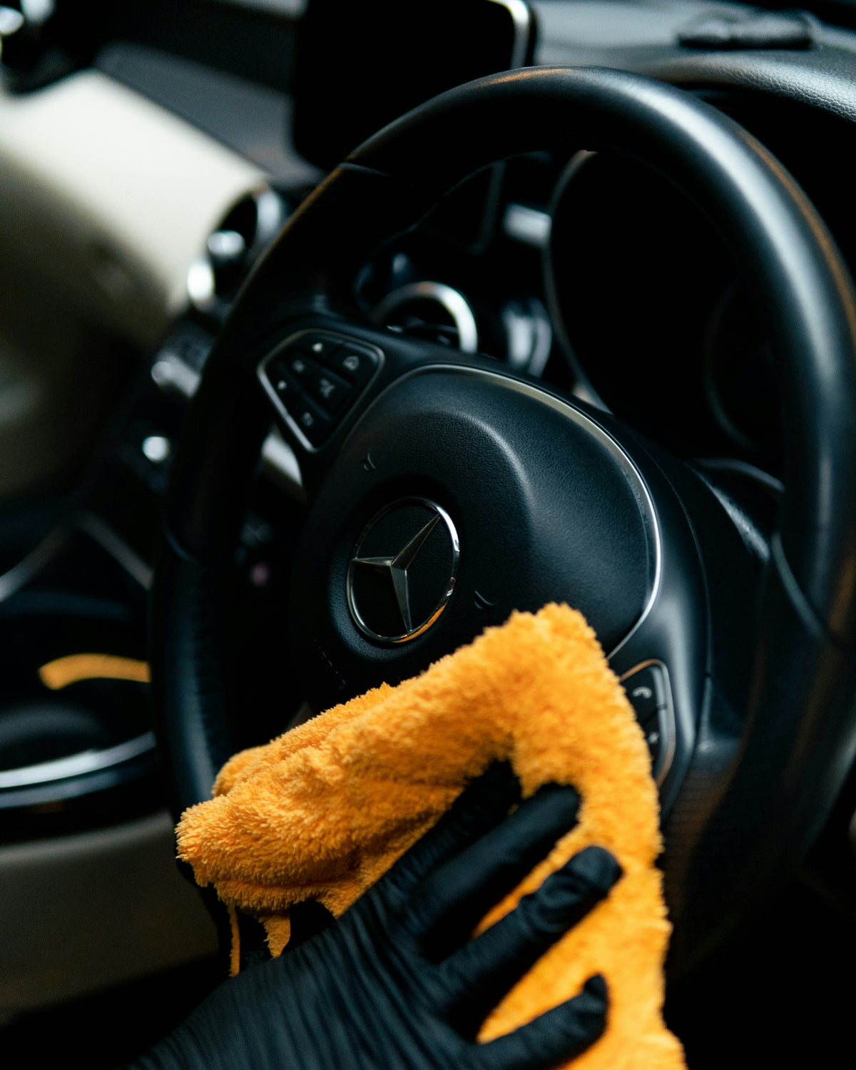 A person cleaning a car with a yellow cloth