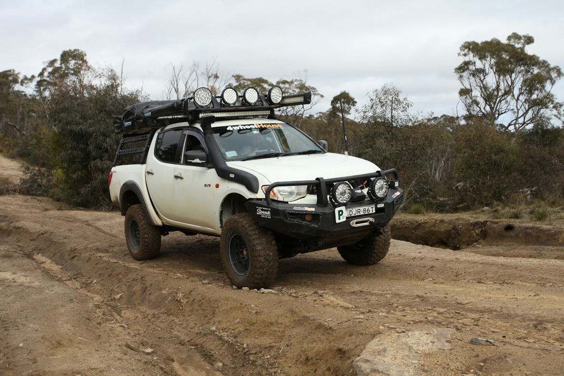 White off-road pickup truck driving on a dirt path